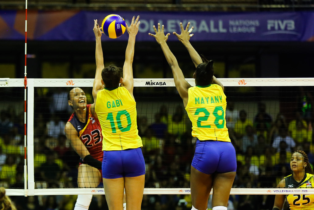Jogadores de vôlei da seleção brasileira saltando na rede para bloquear a bola