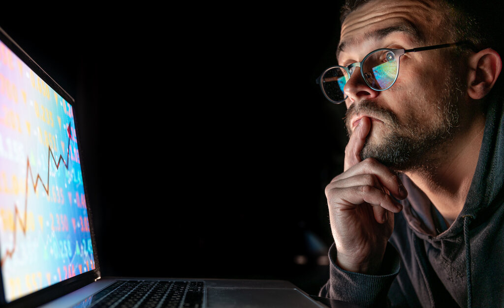 Homem de óculos analise gráficos na tela de um computador