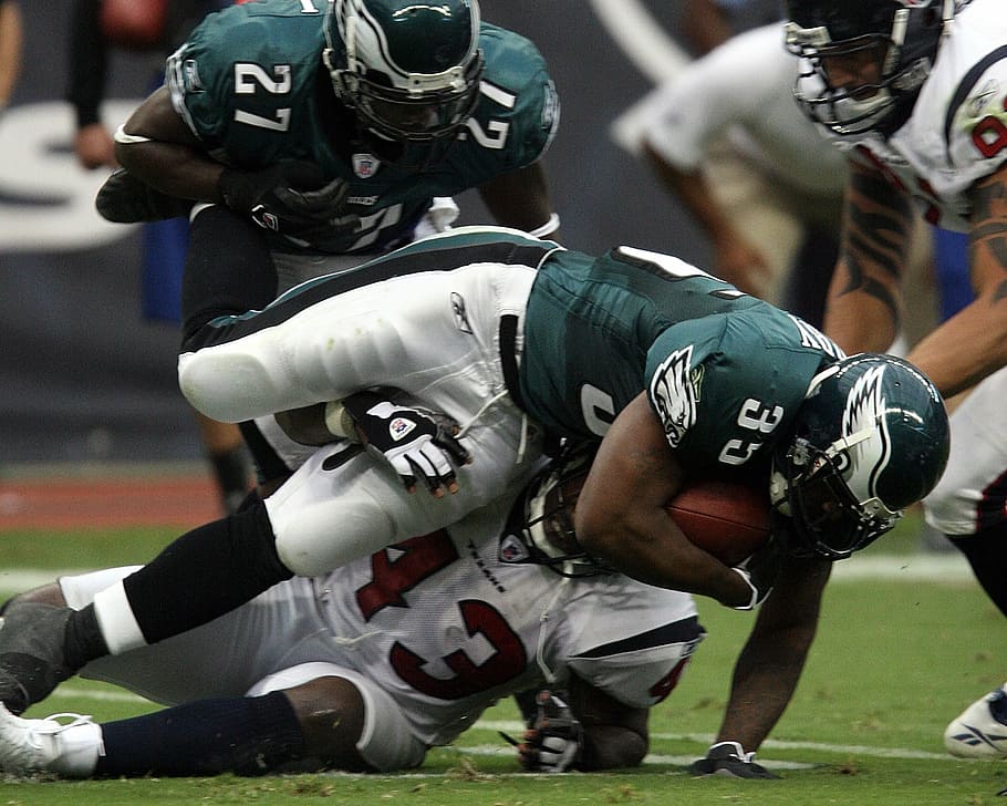 Jogador do Philadelphia Eagles sendo derrubado enquanto segura a bola de futebol americano