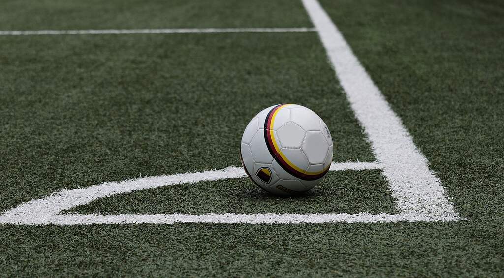 Bola de futebol colocada sobre a marca de escanteio em um campo de futebol.
