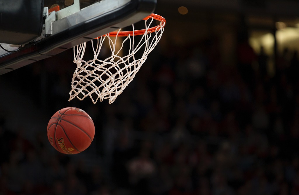 Cesta de basquete com aro laranja, com uma bola de basquete passando por ela.