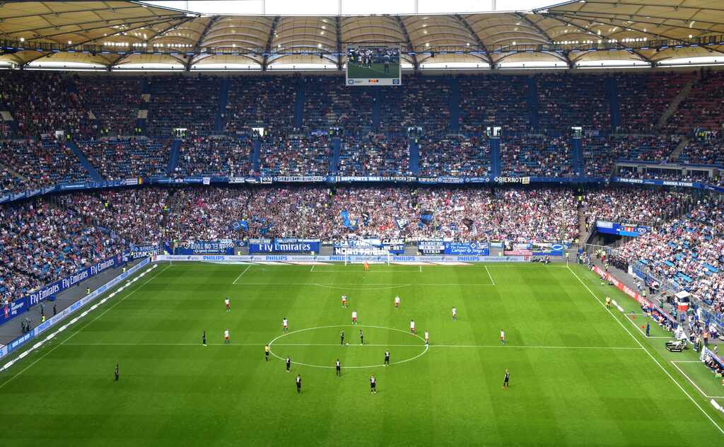 Estádio visto do alto, no sentido de um dos gols, com visão para todo o campo, com jogadores a postos.