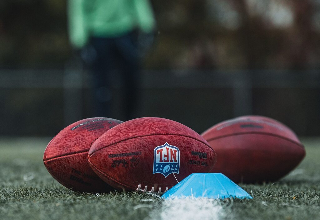 3 bolas de futebol americano como logo da NFL em um campo de grama verde