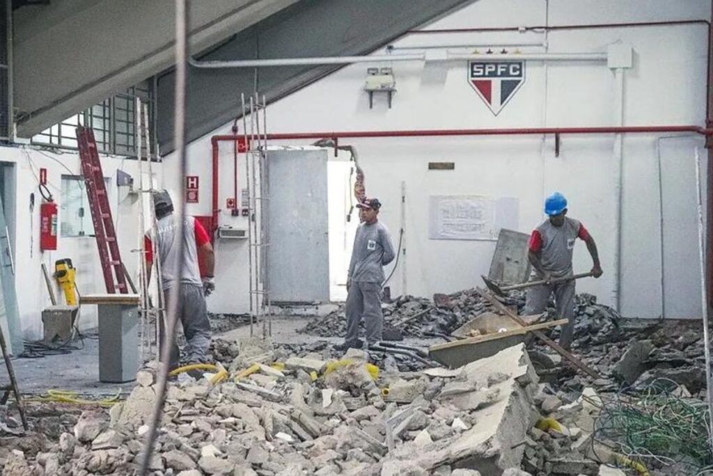 Homens trabalhando em meio aos escombros da obra no CT da Barra Funda do São Paulo.