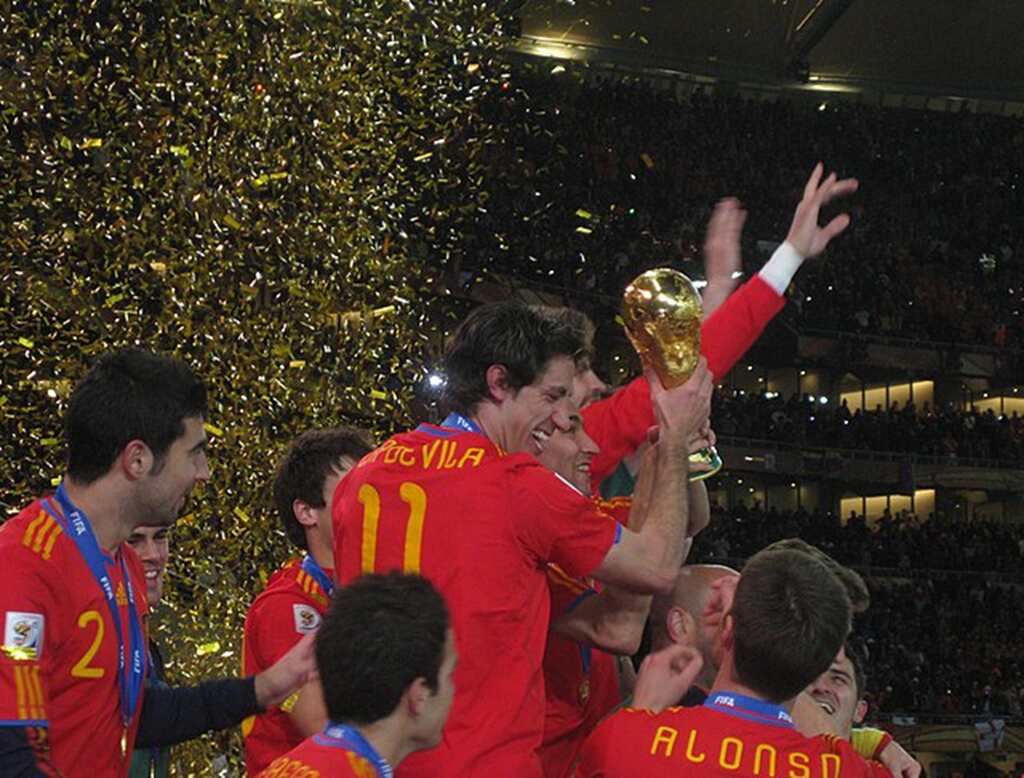 Evolução das principais camisas de seleções Jogadores da seleção da Espanha, vestindo uniforme vermelho, erguendo a taça da Copa do Mundo.