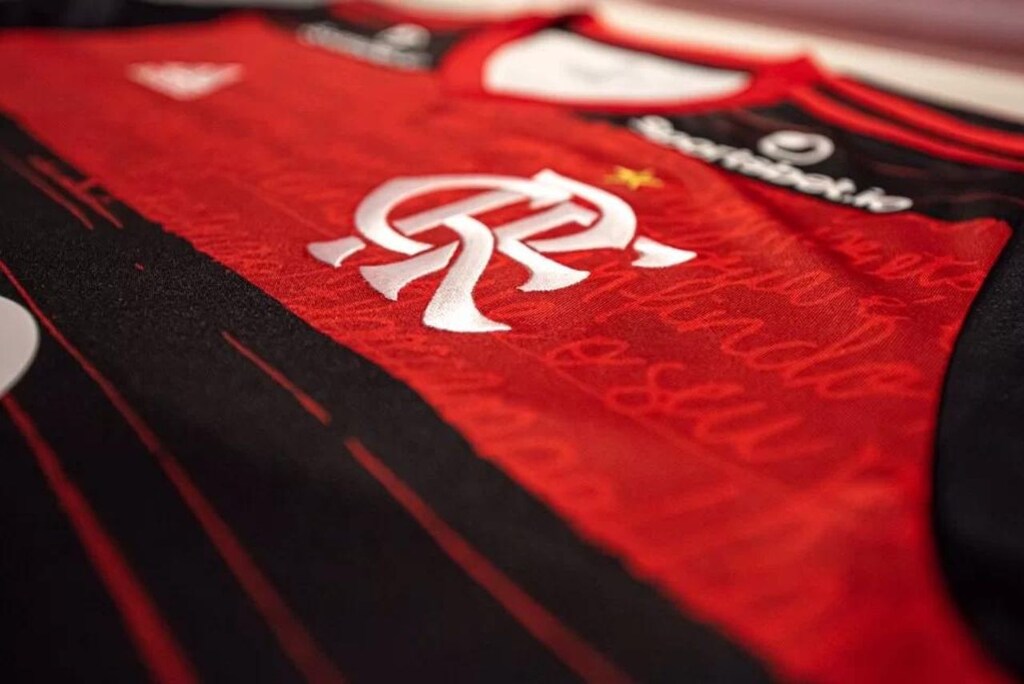 Camisa vermelha e prata, do Flamengo, com escudo do time colocado em seu peito.