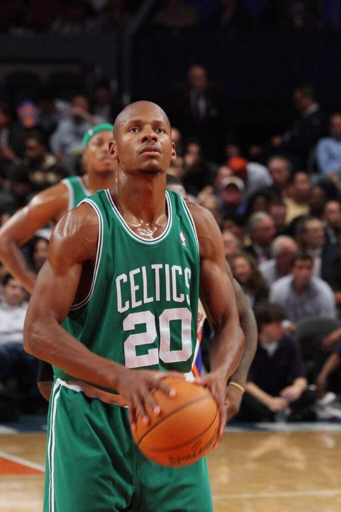 Jogador de basquete Ray Allen, vestindo uniforme verde com detalhes brancos, preparando o arremesso durante a partida.