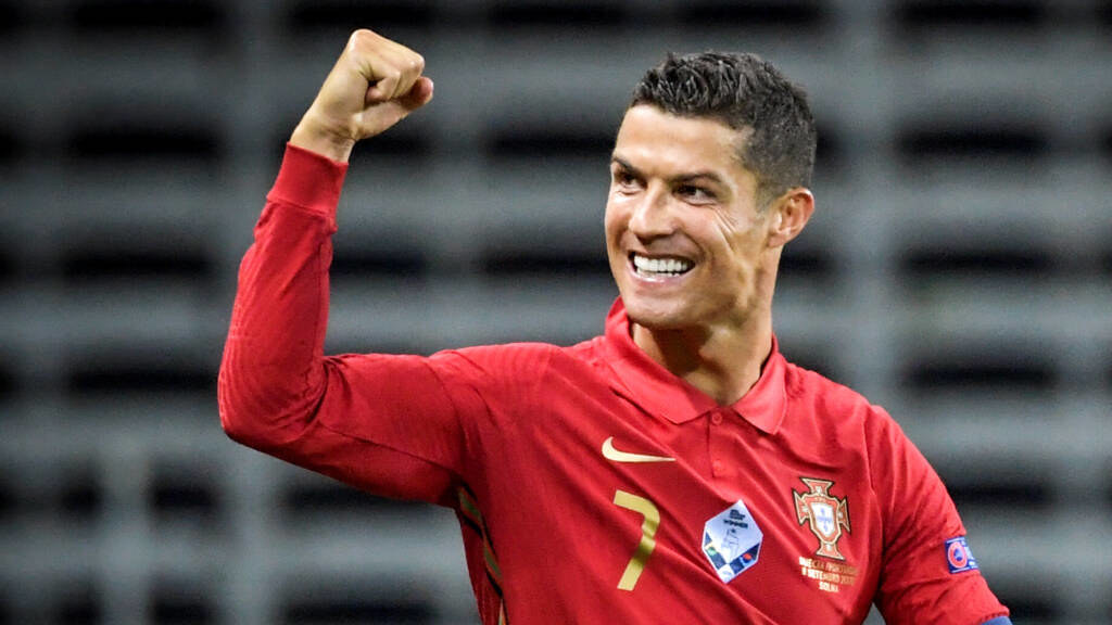 Cristiano Ronaldo, vestindo uniforme vermelho da seleção de Portugal, comemorando gol marcado pela equipe.