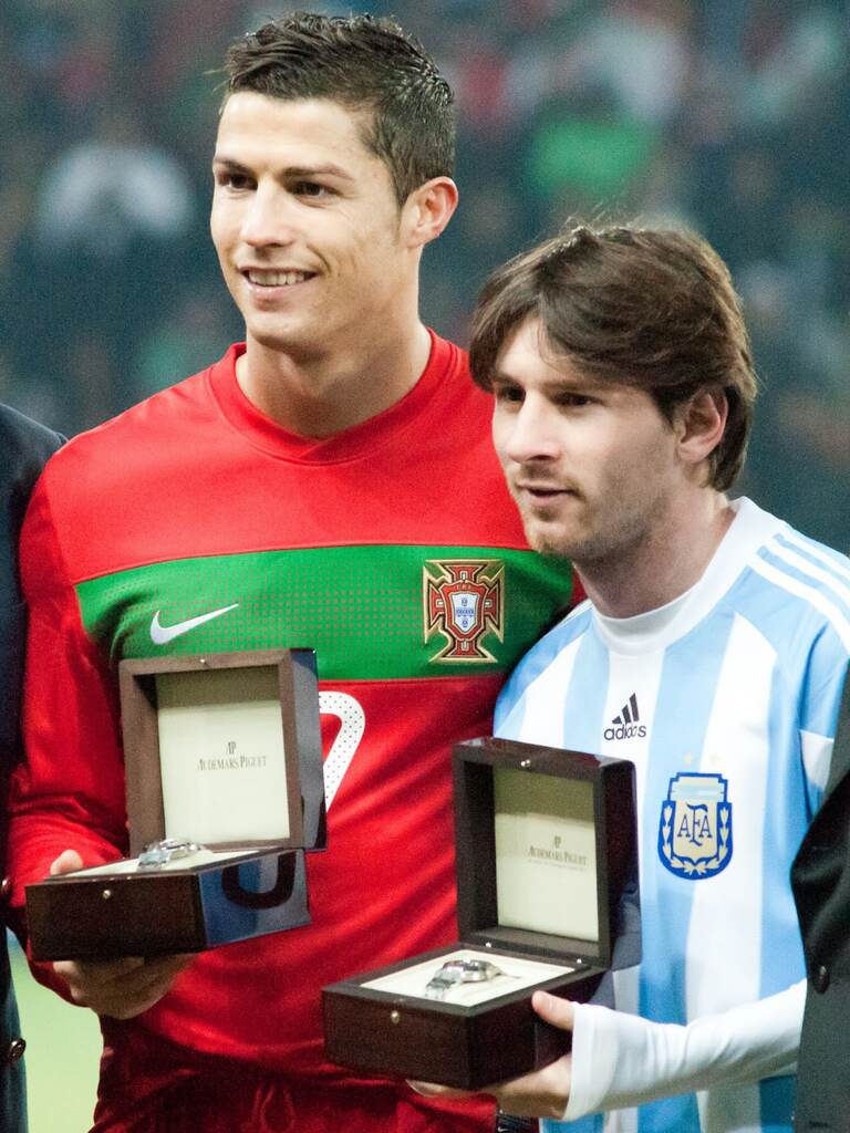 Messi e Cristiano Ronaldo, vestindo uniformes de suas seleções, recebendo prêmios juntos.