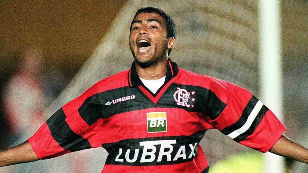 Romário (1995 - 1999) – 204 gols Ex-jogador de futebol, Romário, vestindo camisa do Flamengo e comemorando gol de braços abertos durante partida.