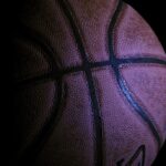 Bola de basquete vista de perto, em ambiente escuro.