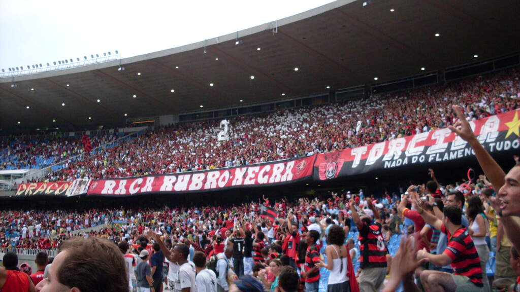 Torcida do Flamengo lotando estádio de futebol e fazendo festa nas arquibancadas durante partida.