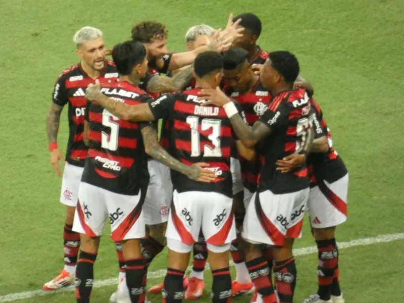 Torcedores do Flamengo cantando e vibrando em estádio lotado, em um dia de jogo.