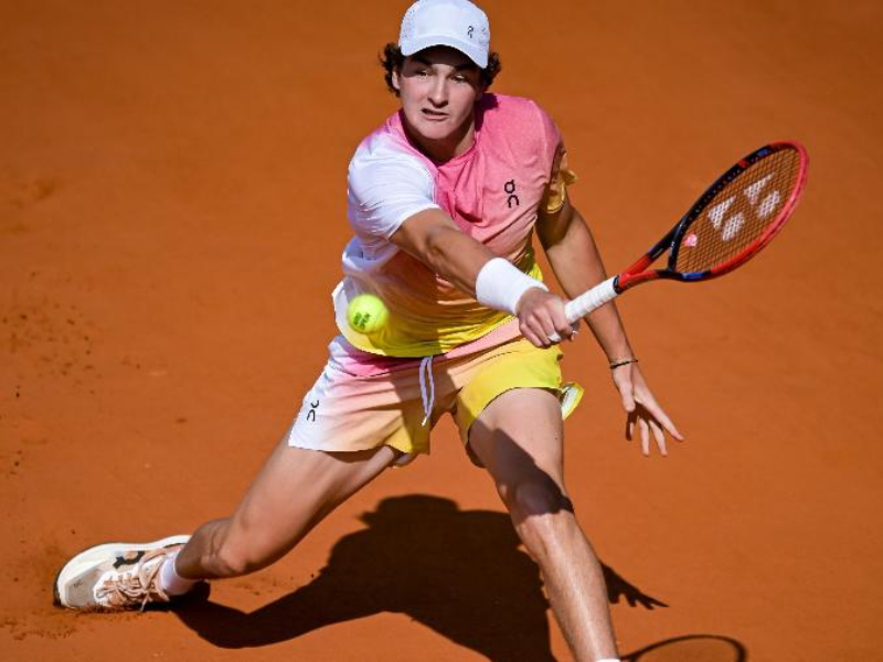 João Fonseca ajoelhado e comemorando a vitória no ATP de Buenos Aires, com a torcida ao fundo.