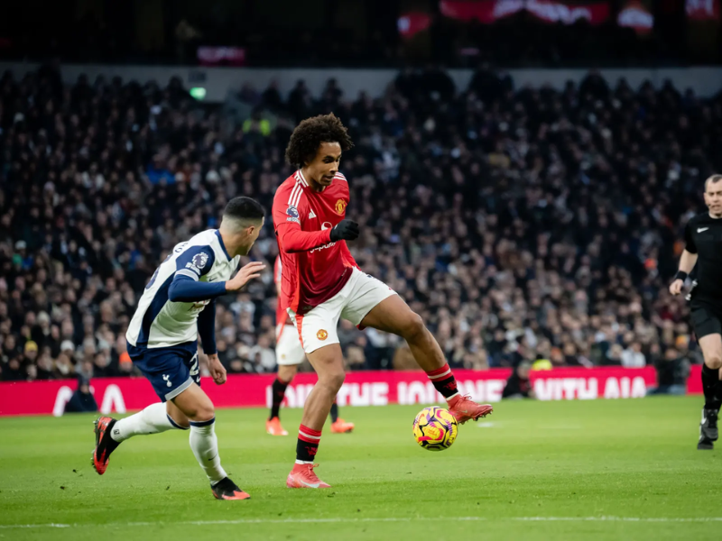 Jogador do Tottenham dribla defensor do Manchester United durante partida acirrada.
