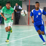Ginásio de futsal com jovens atletas em jogo, torcida vibrante e iluminação intensa, capturando a energia dos Jogos da Juventude.