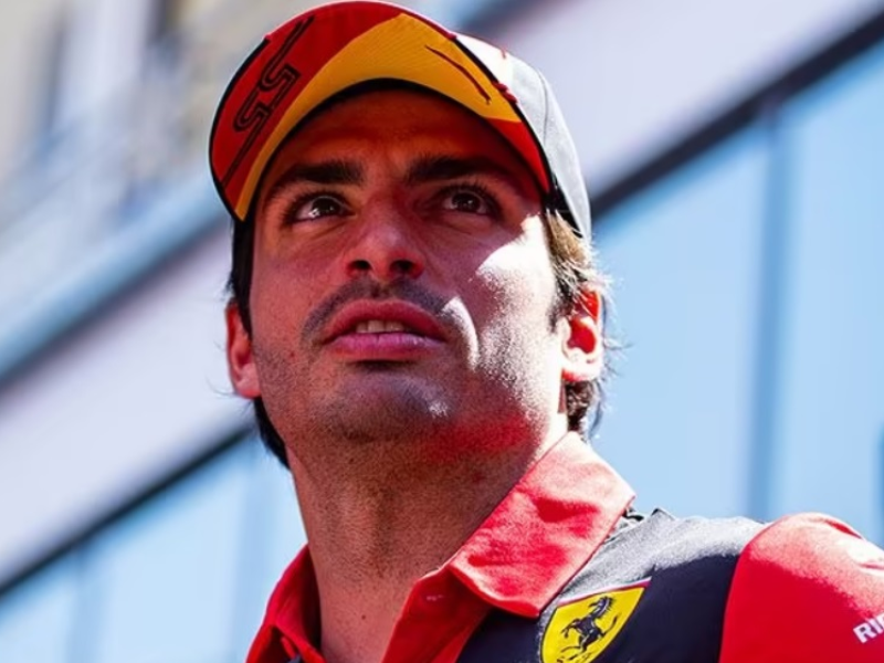 Carlos Sainz Jr. na garagem da Ferrari, olhando determinado.