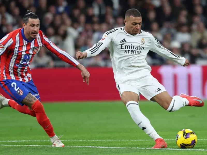 Vinicius Jr. dribla defensor do Atlético de Madrid durante partida da Champions League.