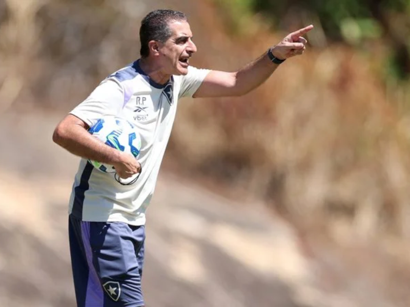 Renato Paiva, técnico do Botafogo, em momento de concentração no vestiário, com luz suave e uniforme de treino.