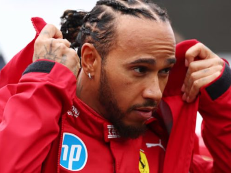 Lewis Hamilton sorrindo com o uniforme da Ferrari.