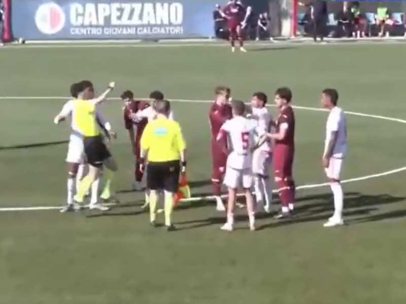 Jogador de futebol do Internacional cabisbaixo sendo consolado por colegas após incidente de racismo.