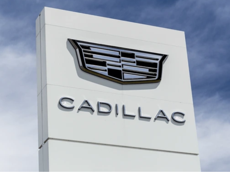 Carro de Fórmula 1 da Cadillac na pista, com cores vibrantes e design futurista, sob luz solar, em vista de frente e lateral.