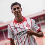 Retrato de Vitor Reis, jogador de futebol brasileiro, vestindo o uniforme do Girona FC, em um campo de treino.
