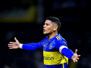 Imagem ultrarrealista de Marcos Rojo, jogador de futebol, com expressão frustrada em vestiário antigo, com um contrato amassado e uma bola de futebol.